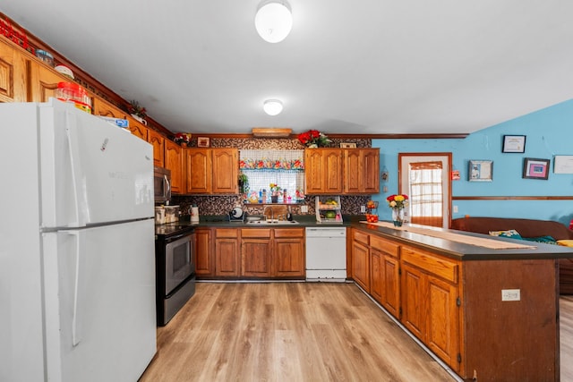 kitchen featuring a peninsula, light wood-style floors, appliances with stainless steel finishes, dark countertops, and brown cabinets