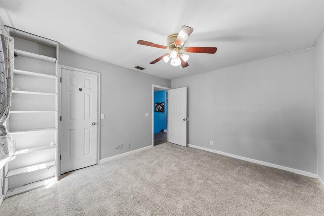 unfurnished bedroom with baseboards, visible vents, carpet floors, and ceiling fan