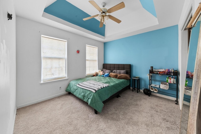 bedroom with carpet flooring, a ceiling fan, a raised ceiling, and baseboards