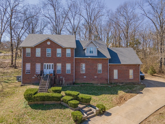 view of front of house with a front lawn, stairway, concrete driveway, a shingled roof, and brick siding