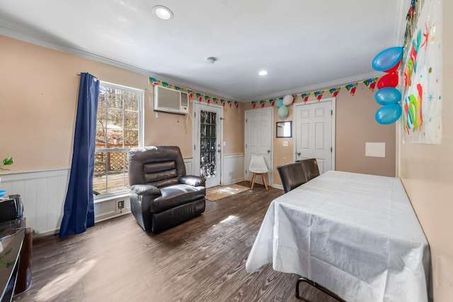 bedroom featuring a wainscoted wall, an AC wall unit, crown molding, and wood finished floors