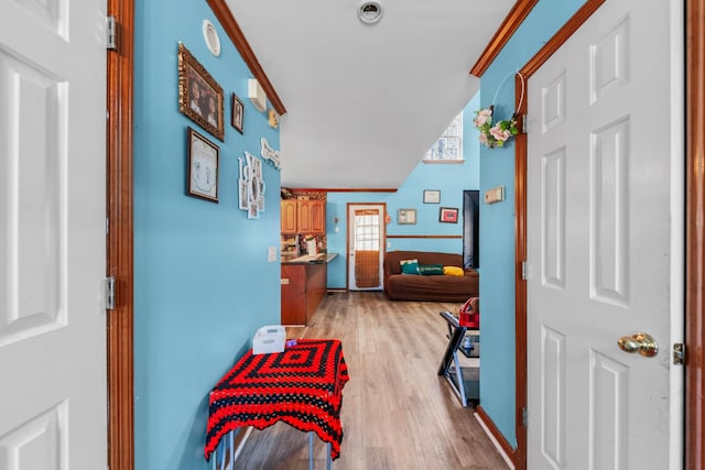 corridor with light wood-type flooring and ornamental molding