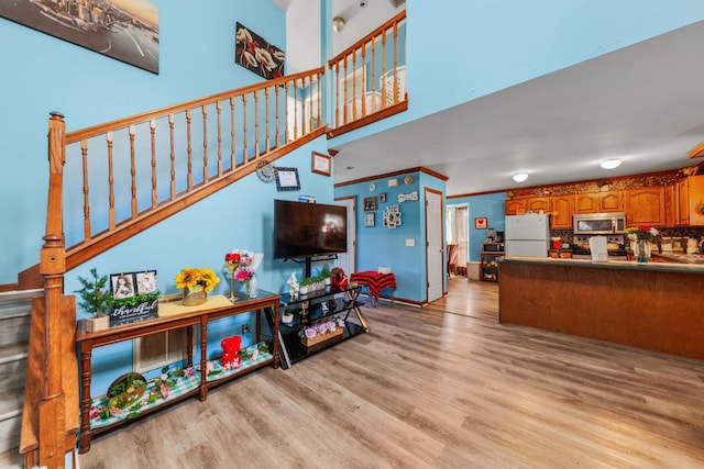 living room with crown molding, stairs, a towering ceiling, and wood finished floors