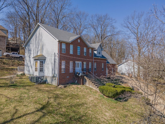 view of front of house featuring brick siding, central AC unit, and a front yard