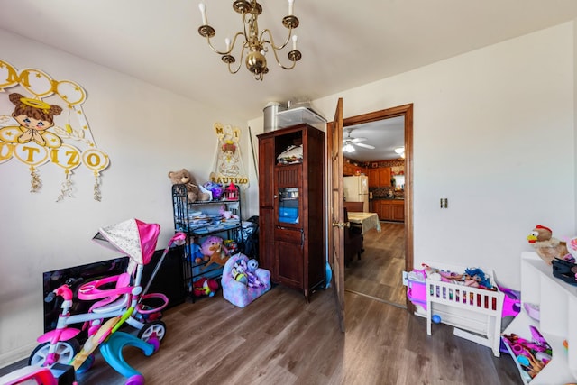 recreation room featuring ceiling fan with notable chandelier and wood finished floors