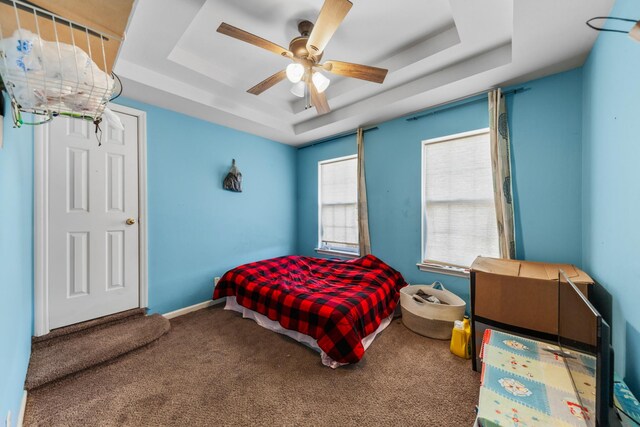 bedroom featuring carpet flooring, ceiling fan, baseboards, and a tray ceiling