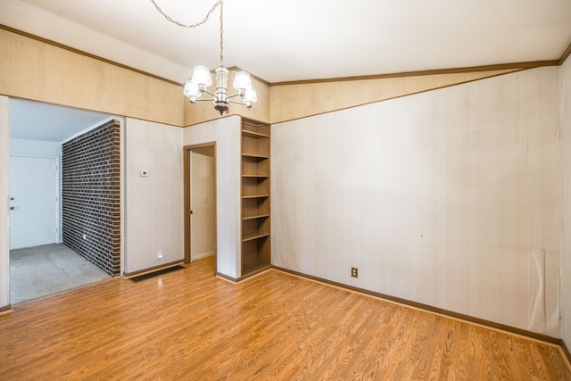 unfurnished room featuring light wood finished floors and a chandelier