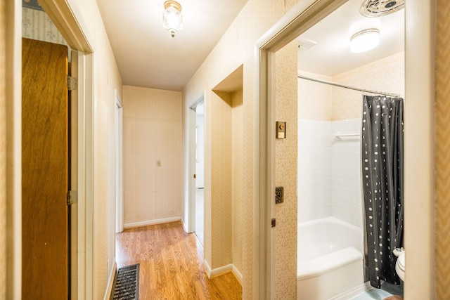 corridor with wallpapered walls, visible vents, and light wood-type flooring