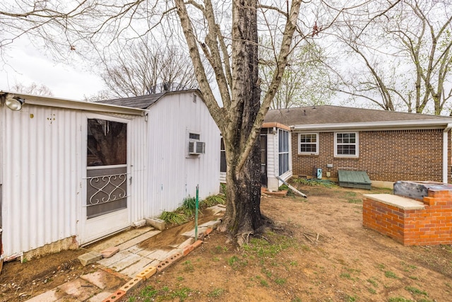 back of property featuring an outdoor structure, brick siding, and a shingled roof
