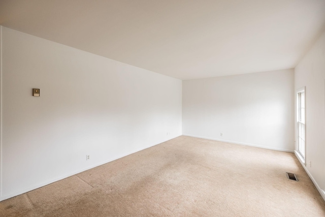 unfurnished room featuring visible vents, light carpet, and baseboards