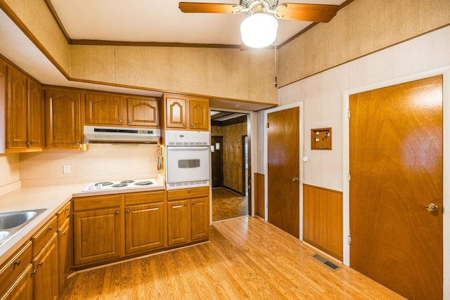 kitchen with visible vents, under cabinet range hood, light countertops, wood finished floors, and white appliances