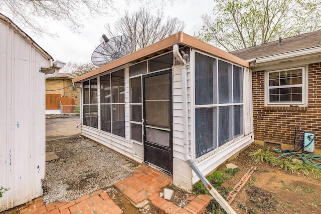 view of outbuilding with fence and a sunroom