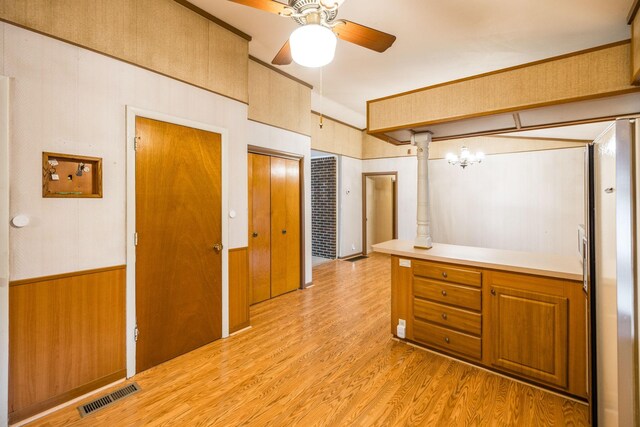 interior space featuring wooden walls, visible vents, a ceiling fan, and wood finished floors