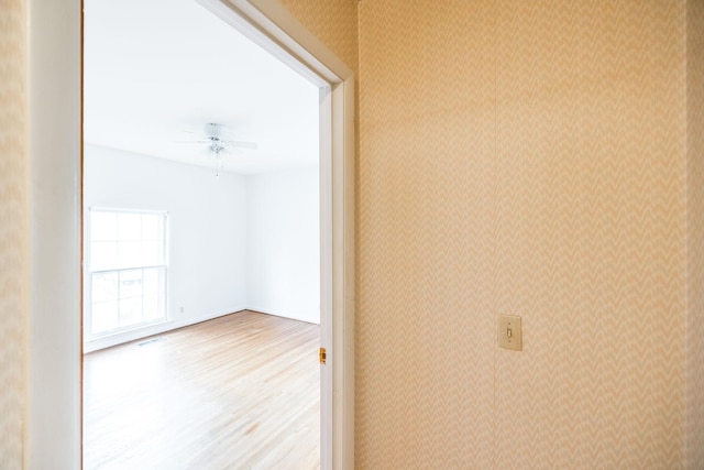 corridor featuring wallpapered walls, wood finished floors, and visible vents