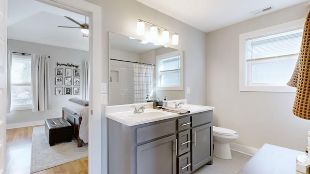 full bath with a shower with shower curtain, a ceiling fan, visible vents, a sink, and toilet