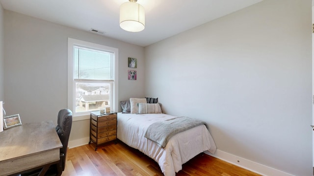 bedroom with baseboards, visible vents, and light wood finished floors