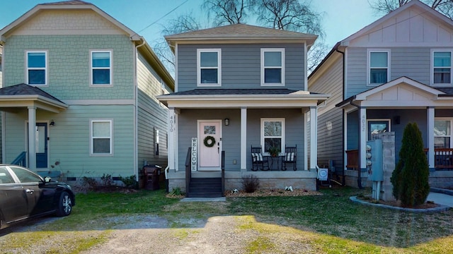 view of front of house with roof with shingles, a porch, and a front yard
