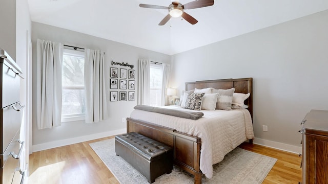 bedroom with light wood finished floors, a ceiling fan, lofted ceiling, and baseboards