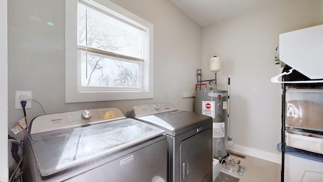 washroom featuring laundry area, washing machine and dryer, water heater, and baseboards