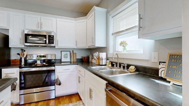 kitchen featuring a sink, dark countertops, white cabinetry, and stainless steel appliances