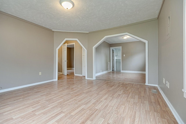 300 E Highland Dr, Columbia, TN 38401 - unfurnished room with visible vents, a textured ceiling, arched walkways, light wood finished floors, and baseboards