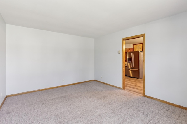 spare room featuring baseboards and light colored carpet