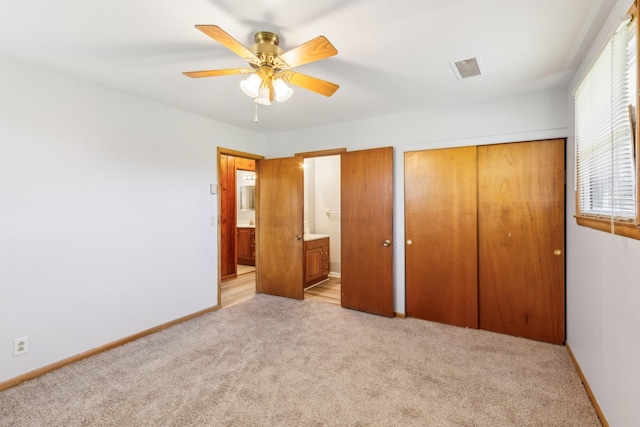 unfurnished bedroom featuring visible vents, ensuite bath, a closet, baseboards, and light colored carpet