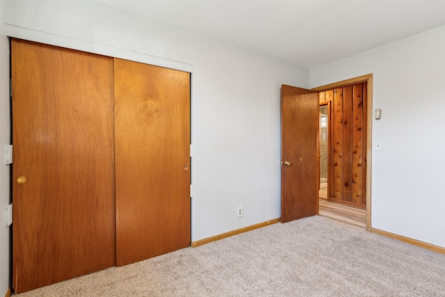 unfurnished bedroom with a closet, baseboards, and carpet flooring