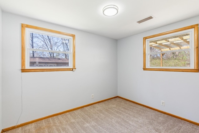 spare room with visible vents, a healthy amount of sunlight, carpet flooring, and baseboards