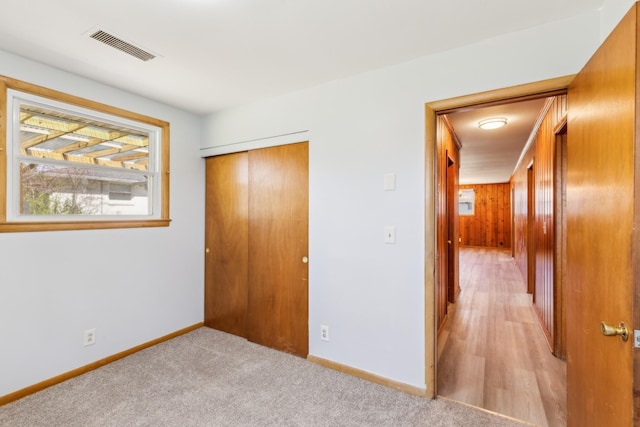 unfurnished bedroom featuring visible vents, baseboards, a closet, and light carpet