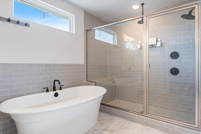 full bathroom featuring a soaking tub, tile walls, marble finish floor, and a stall shower