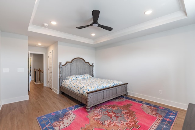 bedroom featuring a tray ceiling, baseboards, and wood finished floors