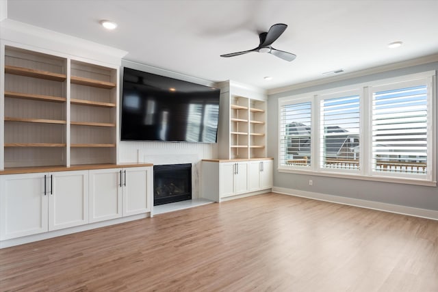 unfurnished living room featuring a premium fireplace, baseboards, light wood-type flooring, and ceiling fan