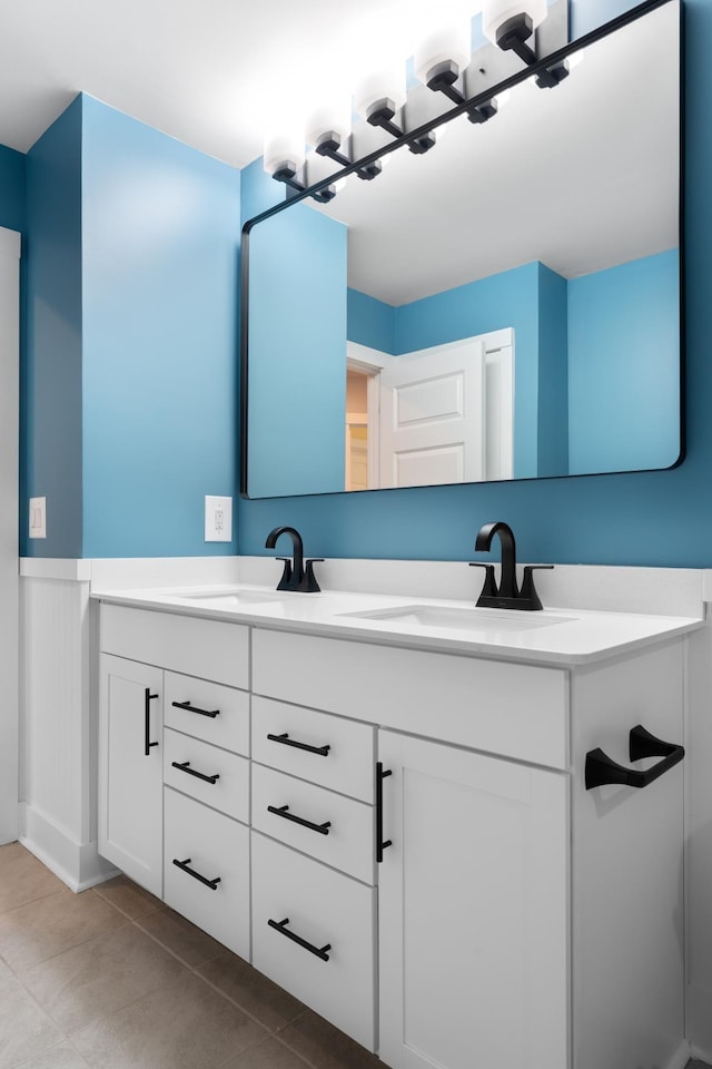 bathroom with tile patterned flooring, double vanity, wainscoting, and a sink