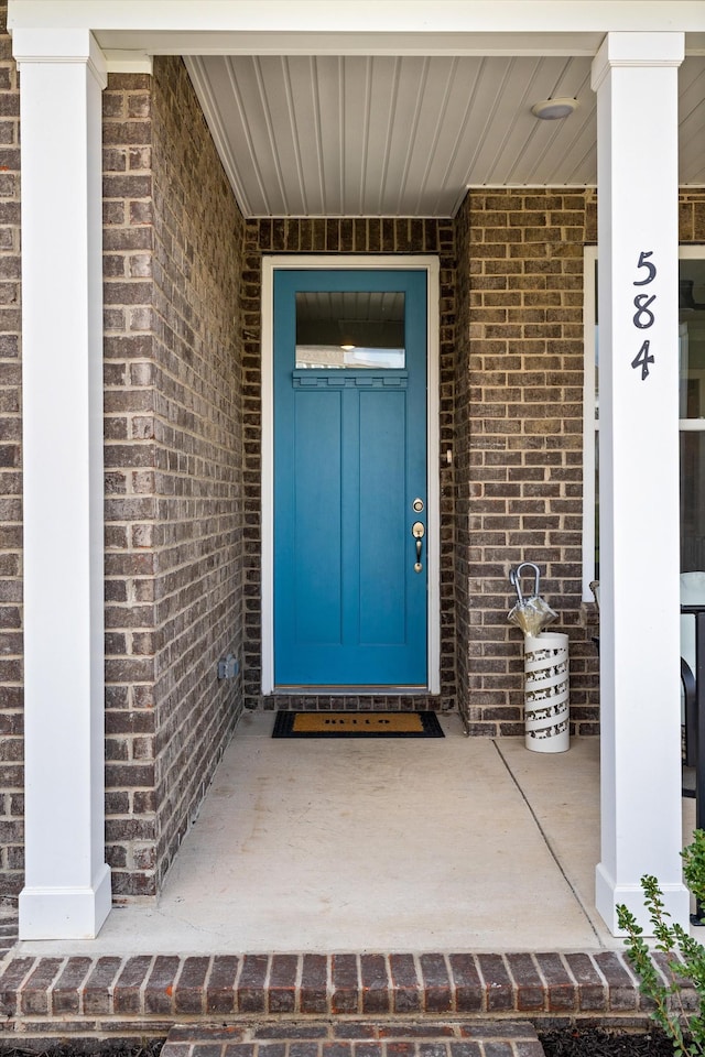 property entrance featuring brick siding and a porch
