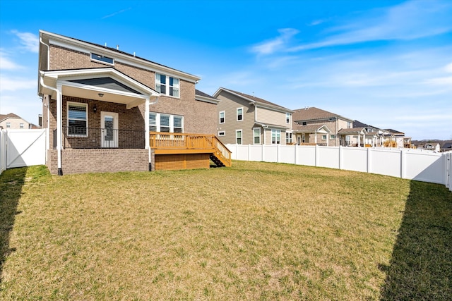 rear view of house with a deck, a fenced backyard, brick siding, and a lawn