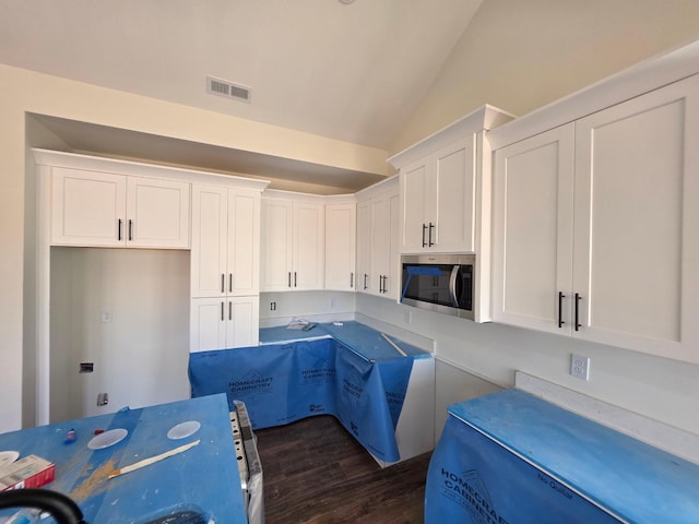 kitchen featuring dark wood finished floors, stainless steel microwave, white cabinets, and visible vents