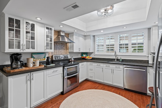 401 Bowling Ave Unit 31, Nashville, TN 37205 - kitchen with visible vents, a tray ceiling, a sink, stainless steel appliances, and wall chimney range hood