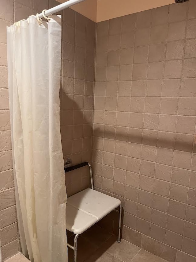 full bathroom with a tile shower and tile walls