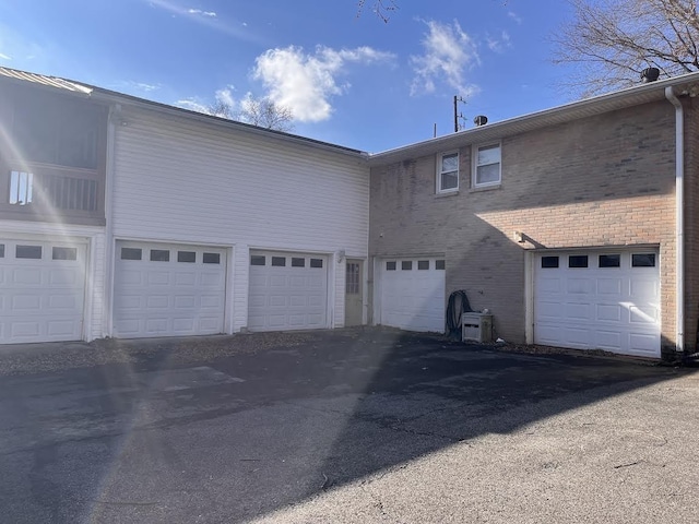 rear view of house featuring brick siding, ac unit, and a garage