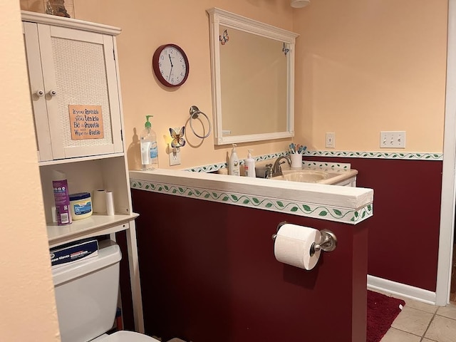 bathroom featuring a sink, tile patterned flooring, toilet, and baseboards