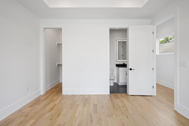 1815 14th Ave N Unit B, Nashville, TN 37208 - unfurnished bedroom with connected bathroom, a closet, light wood-type flooring, a walk in closet, and baseboards