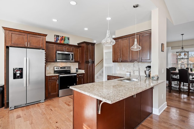 kitchen featuring a peninsula, light wood-type flooring, a sink, and appliances with stainless steel finishes