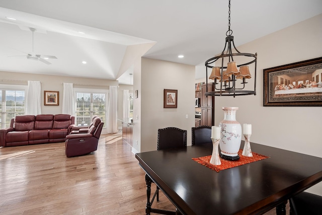 dining room with ceiling fan with notable chandelier, light wood finished floors, vaulted ceiling, and recessed lighting