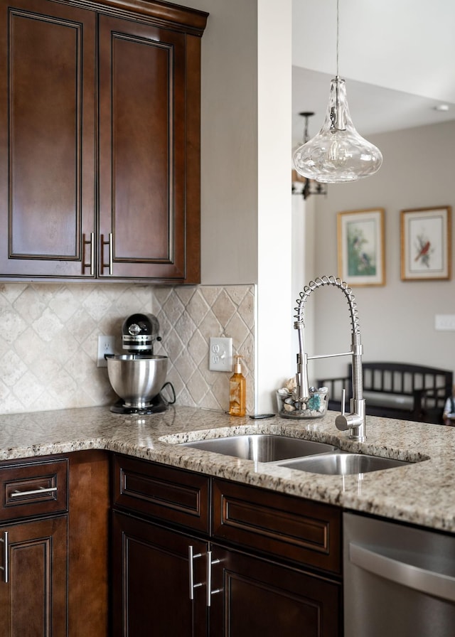 kitchen featuring light stone counters, backsplash, dark brown cabinets, dishwasher, and a sink