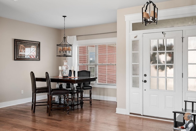 dining space with baseboards, a chandelier, and wood finished floors