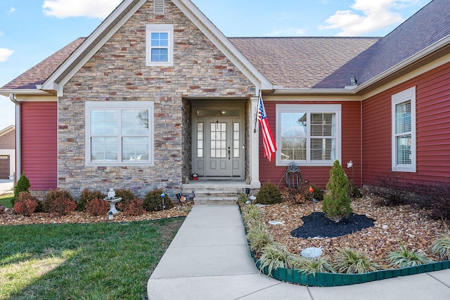 view of front of property with a front lawn, a shingled roof, and stone siding