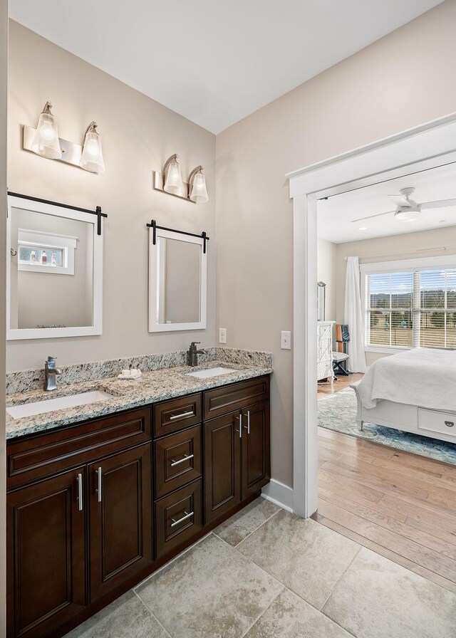 ensuite bathroom featuring double vanity, ensuite bathroom, a sink, and wood finished floors