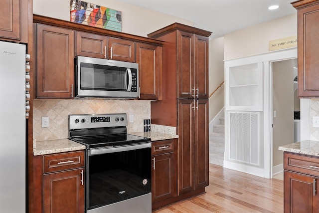 kitchen featuring tasteful backsplash, light wood-type flooring, visible vents, appliances with stainless steel finishes, and light stone counters