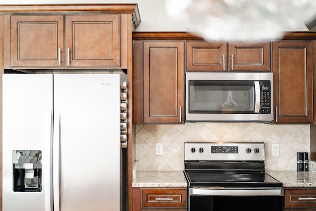 kitchen featuring decorative backsplash, appliances with stainless steel finishes, and light stone countertops